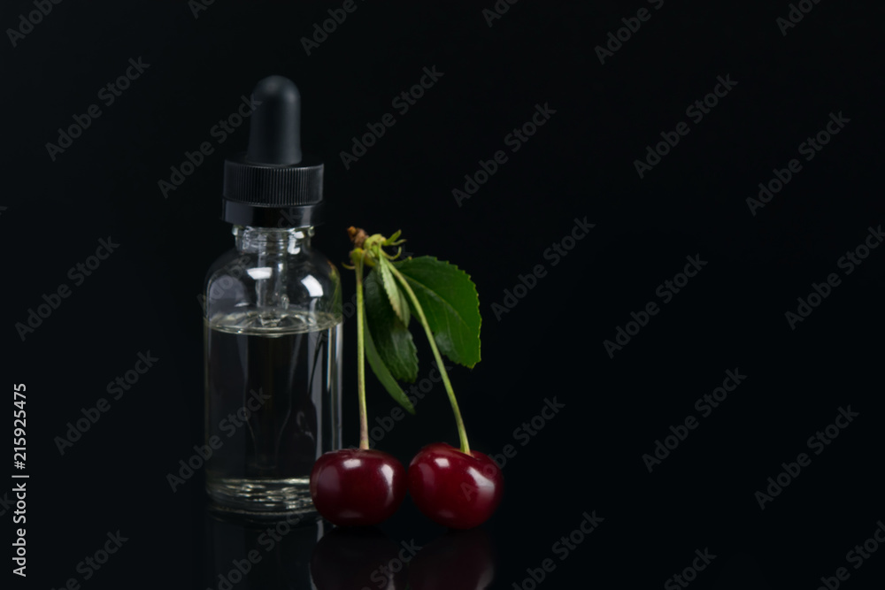 aroma oils in a can with a dispenser, next to the fruit of ripe cherries. lying on black background with reflection. aroma oils in a can with a dispenser, next to the fruit of ripe cherries. lying on black background with reflection.