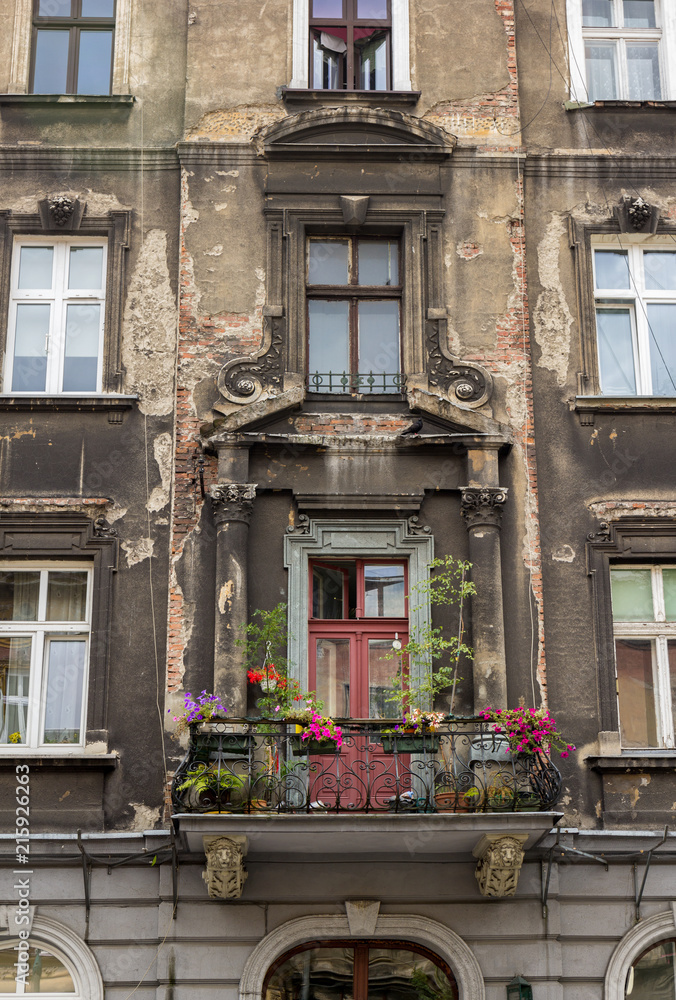 Old vintage house with cracking fasade and a balcony with colorful plants