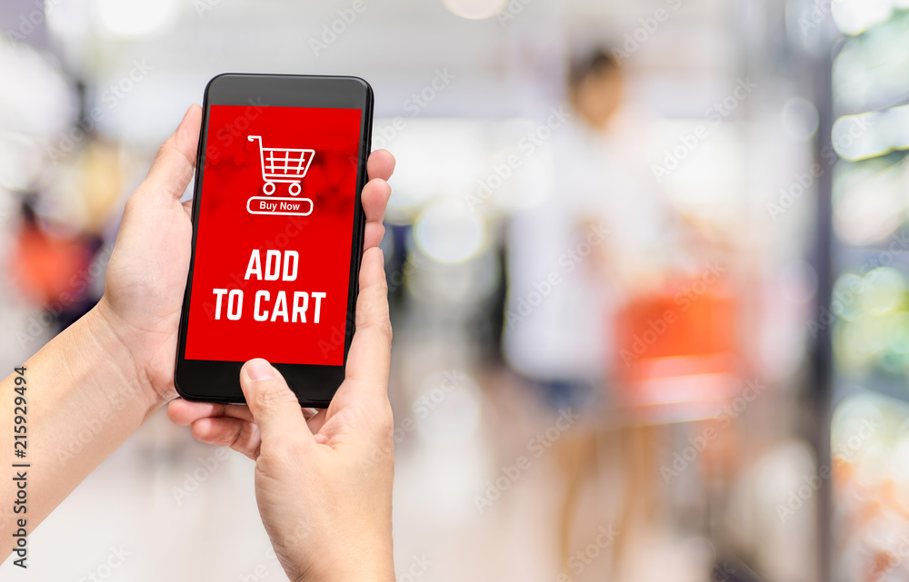 Hand holding mobile add to cart product to purchase online with apps screen at blur bokeh supermarket background,online shopping concept,digital lifestyle.