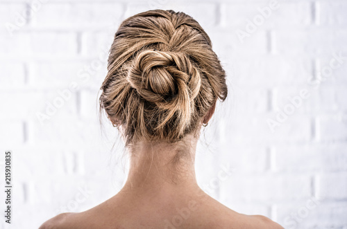 Head of a young woman from behind. Rear view braid hairdo. Hair bun