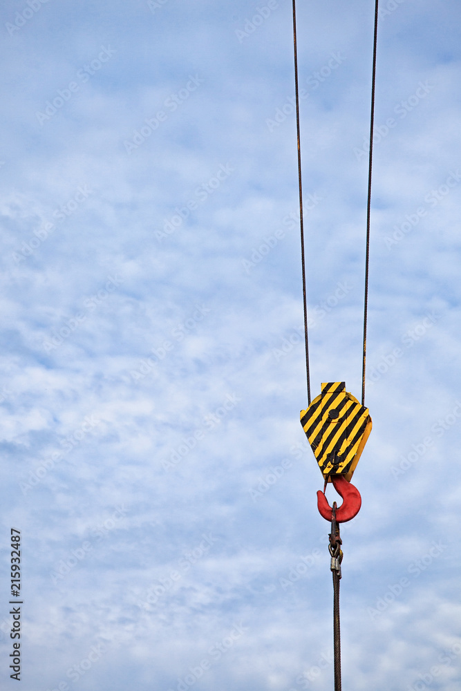 Yellow lifting hook on the cable, with a free place for the inscription on the blue sky. Yellow lifting hook on the cable, with a free place for the inscription on the blue sky.