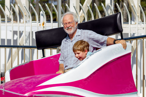 Grandfather Looks at Camera Smiling as He and His Grandson Spin Around in a Tilting Whirling Fair Ride