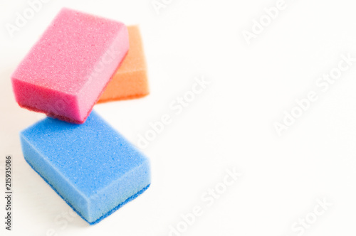 Heap of three red blue and orange sponges for dishwashing on white background with copy space. Cleaning concept