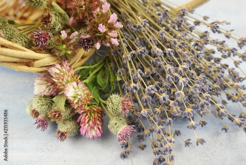 Fototapeta Naklejka Na Ścianę i Meble -  The lavender and lilac wildflowers in the wicker basket on the pale blue background, floristic composition