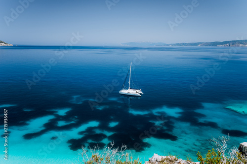 Fteri beach, Cephalonia Kefalonia, Greece. White catamaran yacht in clear blue transparent sea water surface