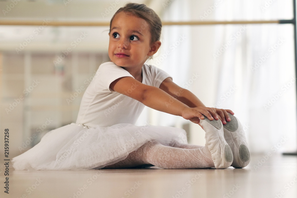 Portrait of a beautiful very young girl, in a dance school wearing a white tutu, she trains alone to learn new dance steps. Concept of: ambition, education, elegance and love for the dance... Portrait of a beautiful very young girl, in a dance school wearing a white tutu, she trains alone to learn new dance steps. Concept of: ambition, education, elegance and love for the dance...
