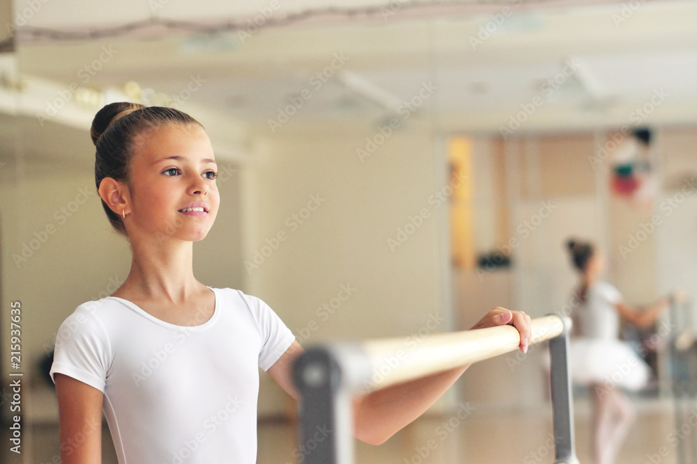 Portrait of a beautiful girl, in a dance school wearing a white tutu, she trains alone to learn new dance steps. Concept of: ambition, education, elegance and love for the dance.