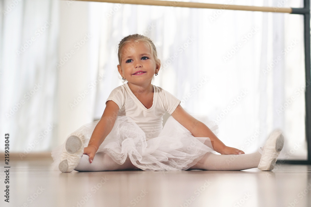 Portrait of a beautiful very young girl, in a dance school wearing a white tutu, she trains alone to learn new dance steps. Concept of: ambition, education, elegance and love for the dance... Portrait of a beautiful very young girl, in a dance school wearing a white tutu, she trains alone to learn new dance steps. Concept of: ambition, education, elegance and love for the dance...