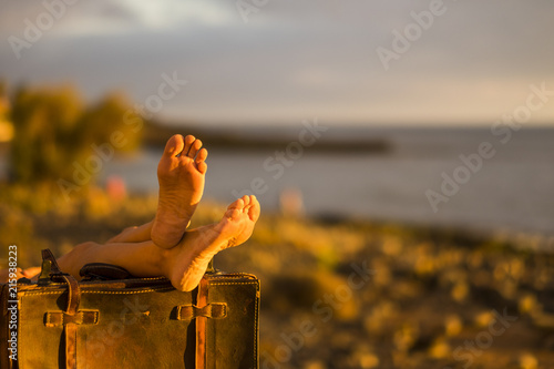 travel concept image. beach and ocean in defocused backgorund and coulpe of female nude feet on old vintage luggage. resting after a trip, living a wonderful journey and vacation photo