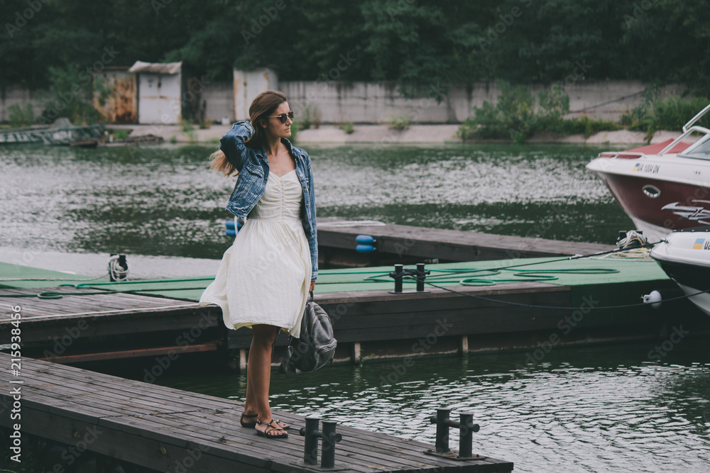 Portrait of adorable woman walking on pier near the river