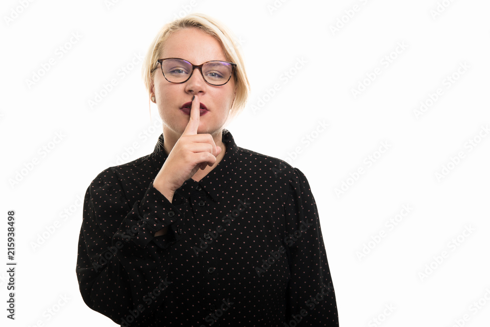 Blonde female teacher wearing glasses showing silence gesture Blonde female teacher wearing glasses showing silence gesture