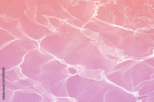 Pink water surface with bright sun light reflections, water in swimming pool background