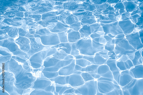 Blue water surface with bright sun light reflections, water in swimming pool background