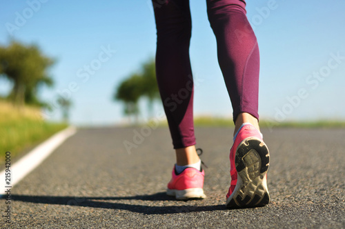 Legs of a young female runner on a road while jogging