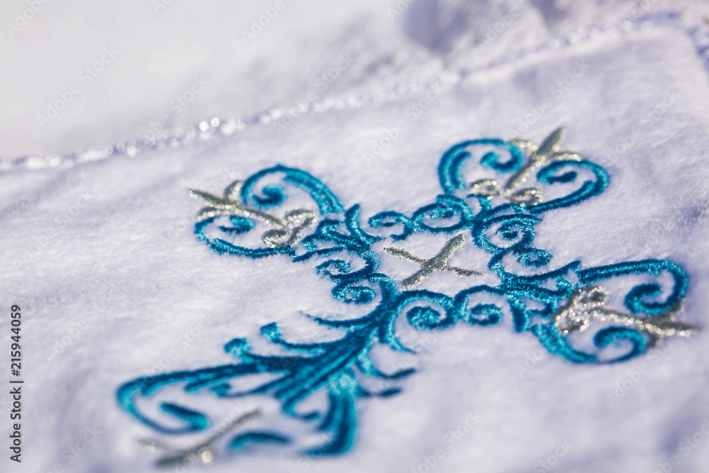 Embroidered blue cross on white carpet. Baptism. Macro Embroidered blue cross on white carpet. Baptism. Macro