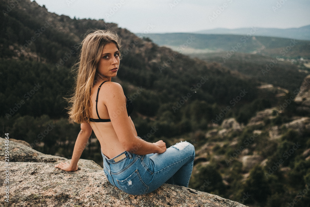 Woman in bra sitting on rocks Woman in bra sitting on rocks