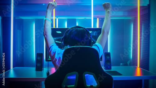 Professional Gamer Playing and Winning in First-Person Shooter Online Video Game on His Personal Computer. Footage Fade out into Bokeh. Room Lit by Neon Lights in Retro Arcade Style. Cyber Sport.