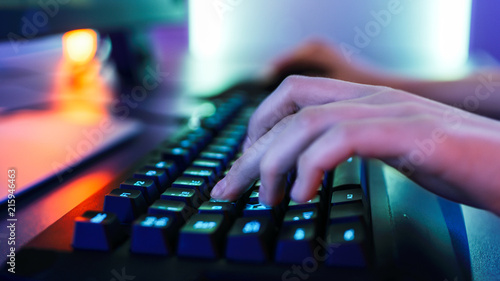Close-up on the Hands of the Gamer Playing in the Video Game on a Keyboard. Stylish Arcade Neon Bright Red, Pink, Violet, Green Colors.