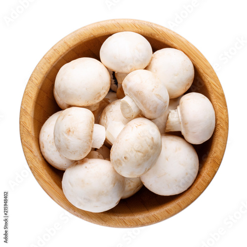 Whole small fresh white champignon mushrooms in wooden bowl isolated on white.