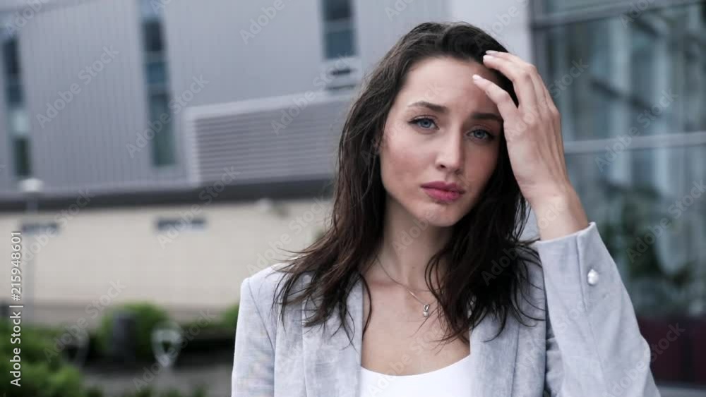 Very Attractive Young Woman with Deep blue Eyes Looking at the Camera. Posing like a Model. Pretty Businesswoman is Sad, Suppressed. Feeling Depressed. Wet Hair. Girl Standing in the City. Very Attractive Young Woman with Deep blue Eyes Looking at the Camera. Posing like a Model. Pretty Businesswoman is Sad, Suppressed. Feeling Depressed. Wet Hair. Girl Standing in the City.