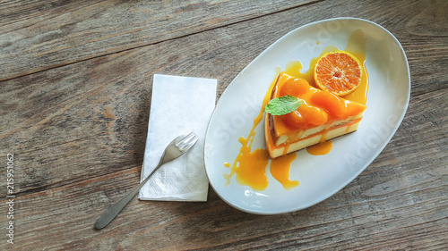 Sweet or dessert, a delicious orange cake topping with orange slices on white plate on wooden table 