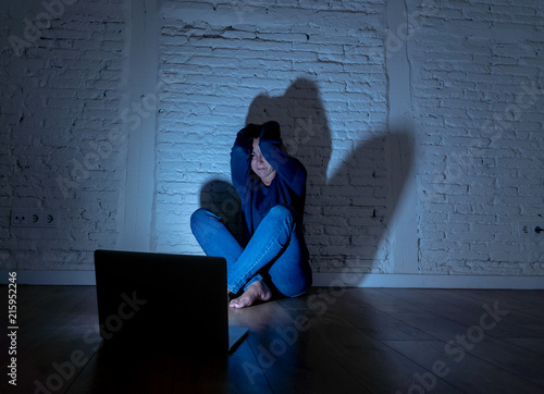 Sad and scared female Young woman with computer laptop suffering cyberbullying and harassment being online abused by stalker or gossip feeling desperate and humiliated in cyber bullying concept. photo
