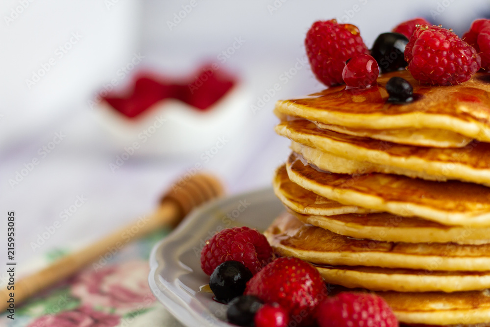 Stack of gold pancakes with berries and honey on wooden background Stack of gold pancakes with berries and honey on wooden background