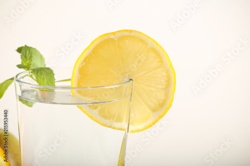 вода чистая в стакане и свежие фрукты на белом фоне 