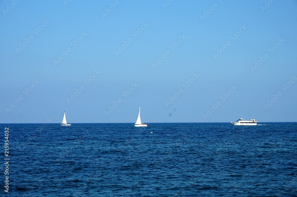 White ships (sailboats or yachts) floating in the sea.