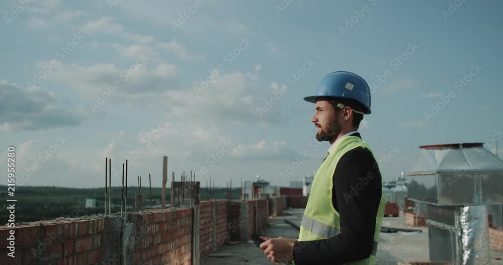 Architect using a tablet to analyze the plan of building on the rooftop of building. Architect using a tablet to analyze the plan of building on the rooftop of building.