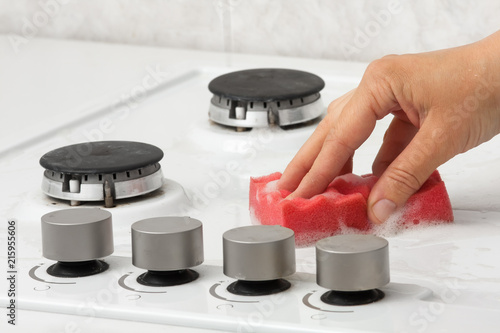 hands cleaning gas stove with sponge