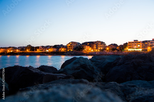 Sunset and the night light in Ravda. Bulgaria. Reflection of light of the city in the sea.