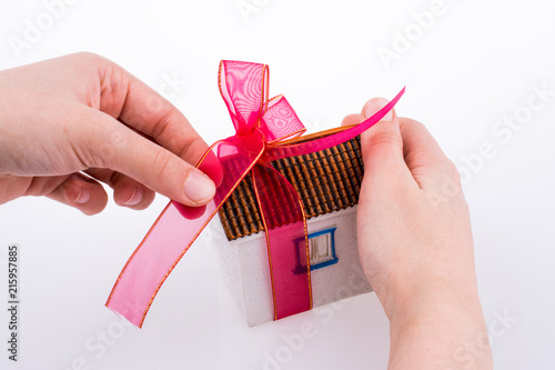 Hand holding a house with a ribbon photo