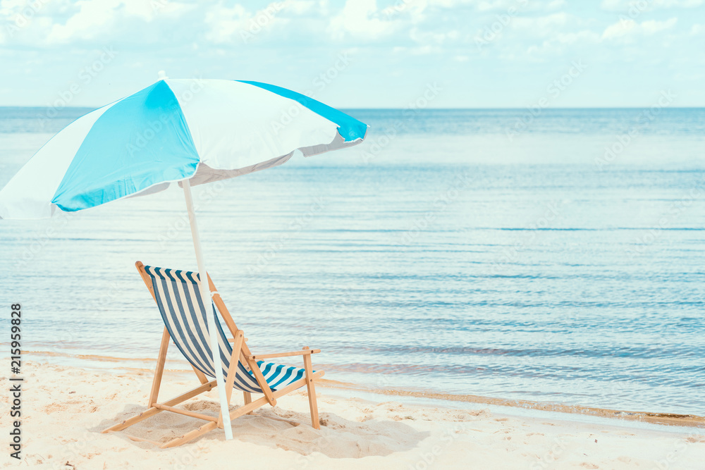 sun umbrella and beach chair on sandy shore near the sea sun umbrella and beach chair on sandy shore near the sea