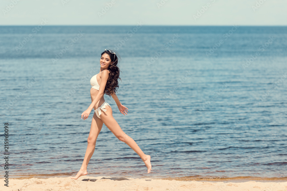 happy slim young woman in white bikini jumping on sea beach happy slim young woman in white bikini jumping on sea beach