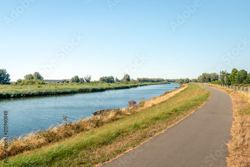 Narrow bike path next to a wide creek in a nature reserve