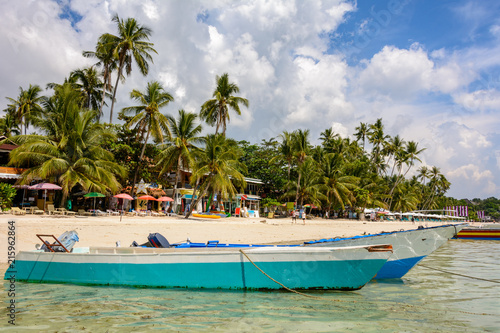 Boats in the sea at a beautiful tropical beach. White sandy beach and crystal clear water sea. Philippines. Asia