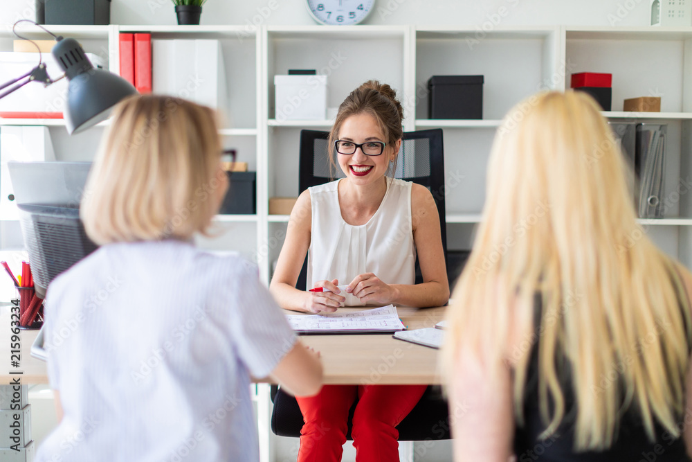 A young girl sits at a table in her office and talks to two co-partners. A young girl sits at a table in her office and talks to two co-partners.