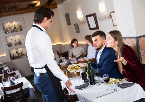 Valokuva angry guests conflicting with waiter in restaurant