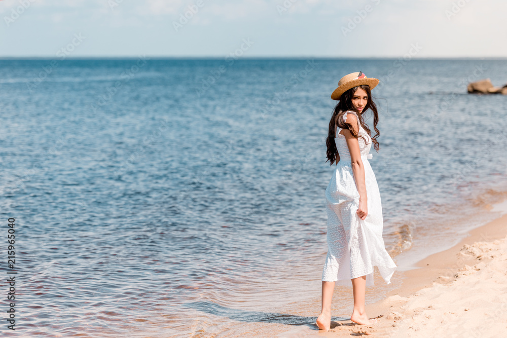 young woman in straw hat and white dress walking on beach young woman in straw hat and white dress walking on beach