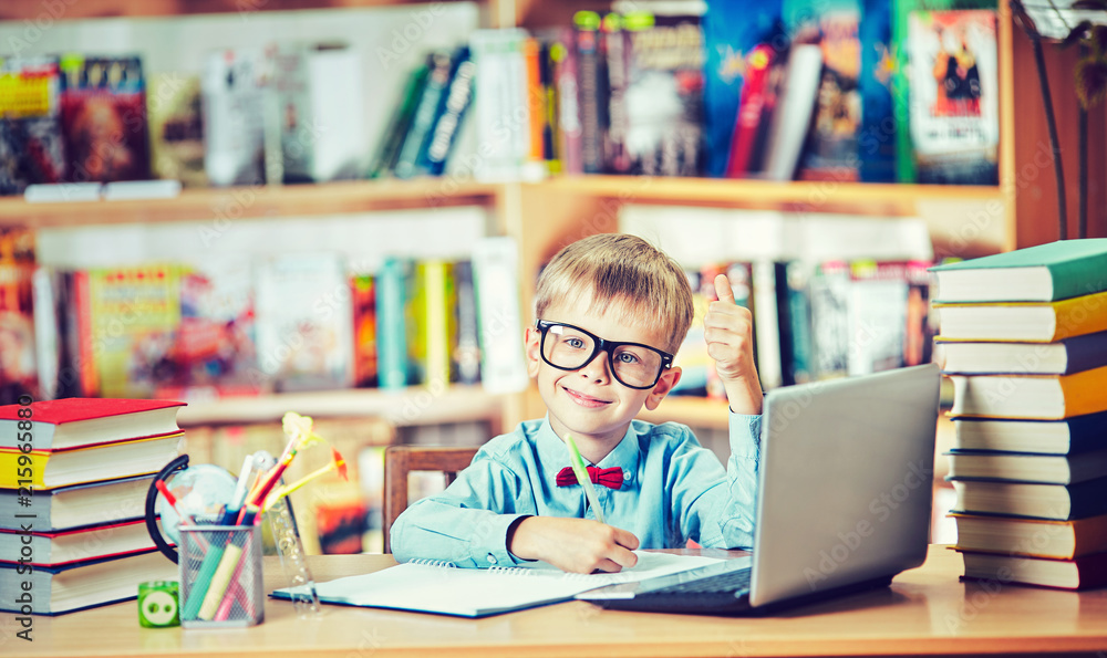 Back to school and happy time! Cute industrious child is sitting at a desk indoors. Back to school and happy time! Cute industrious child is sitting at a desk indoors.