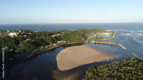 Nambucca heads at Nambucca river on Australian central coast in aerial flying forward over river waters and sandy islands towards headland on Pacific ocean coast.
 photo