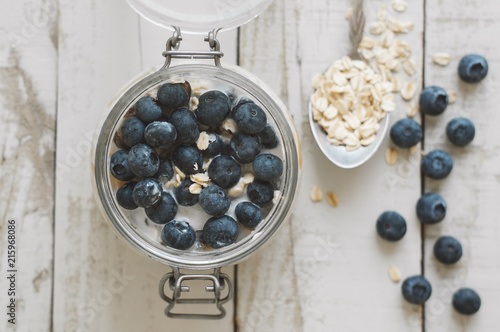 Overnight oats with soaked in coconut milk with fresh bluberry on wooden table, top view. Healthy breakfast