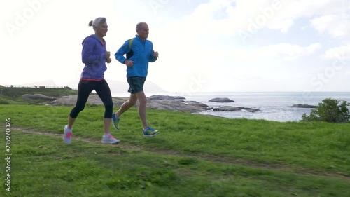 Senior couple jogging together by the sea photo