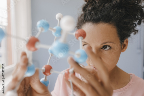 Female scientist holding molecule model, looking for solutions photo