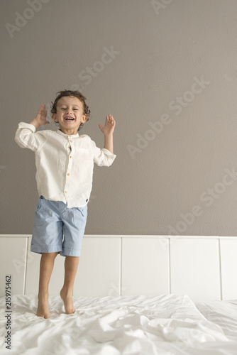 Child standing on top of a bed.
