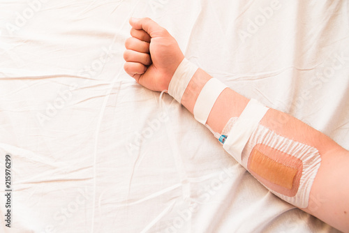 Hand of a patient with an infusion catheter on the white tissue 