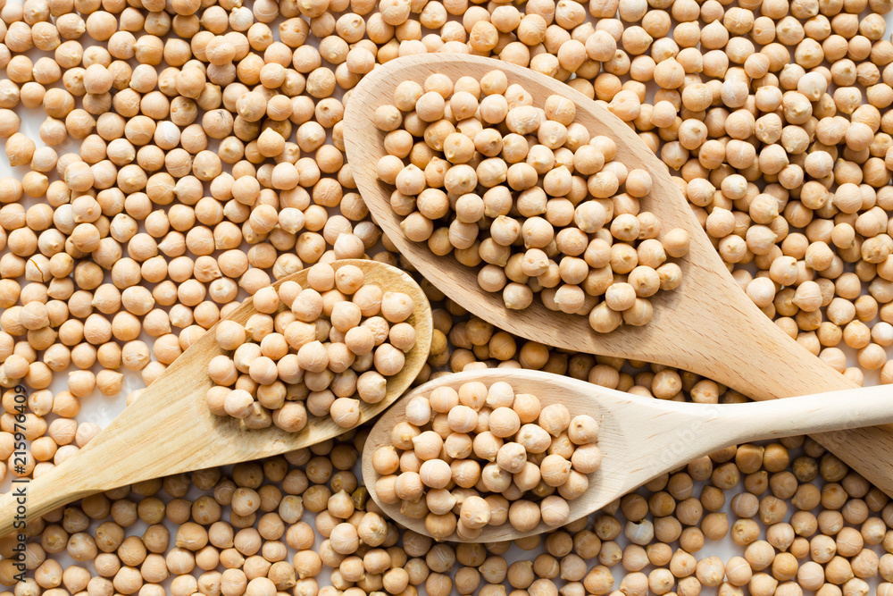 Fototapeta premium dry raw chickpeas in wooden spoons