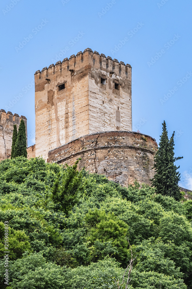 View of famous Alhambra - mediaeval Moorish palace and fortress complex from Calle Chirimias. Alhambra originally constructed as a small fortress in AD 889. Granada, Andalusia, Spain.