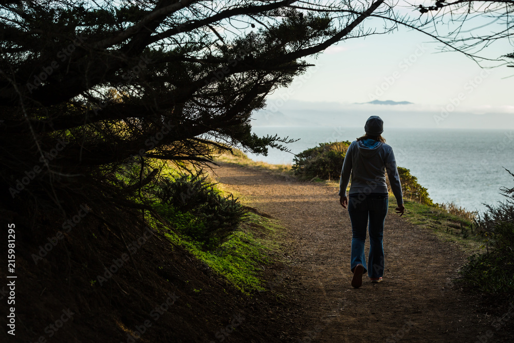 Woman walking along coastal trail taking smartphone photos Woman walking along coastal trail taking smartphone photos